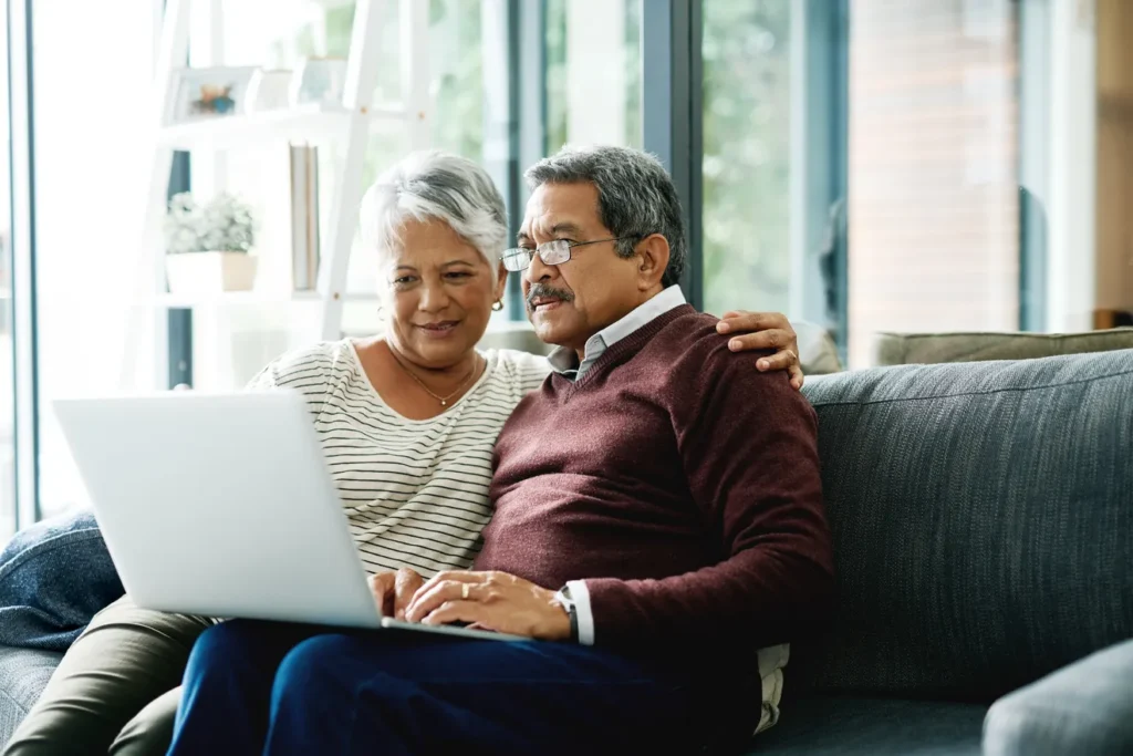 Elderly couple sitting on couch looking at laptop screen