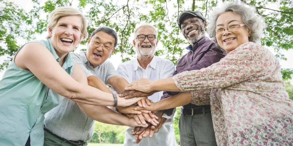 Elderly people standing in a circle holding hands