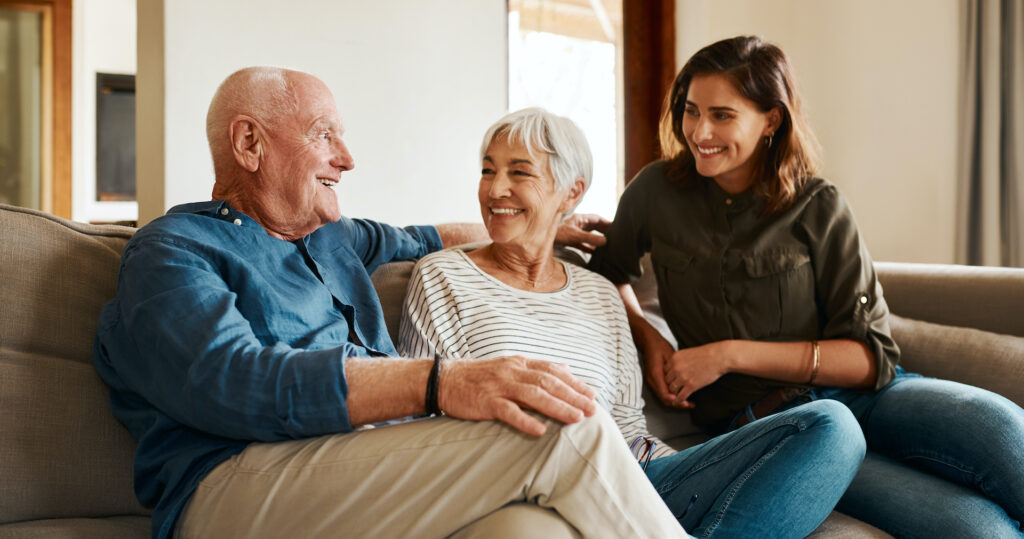 Elderly Couple sitting on couch with Middle Aged daughter
