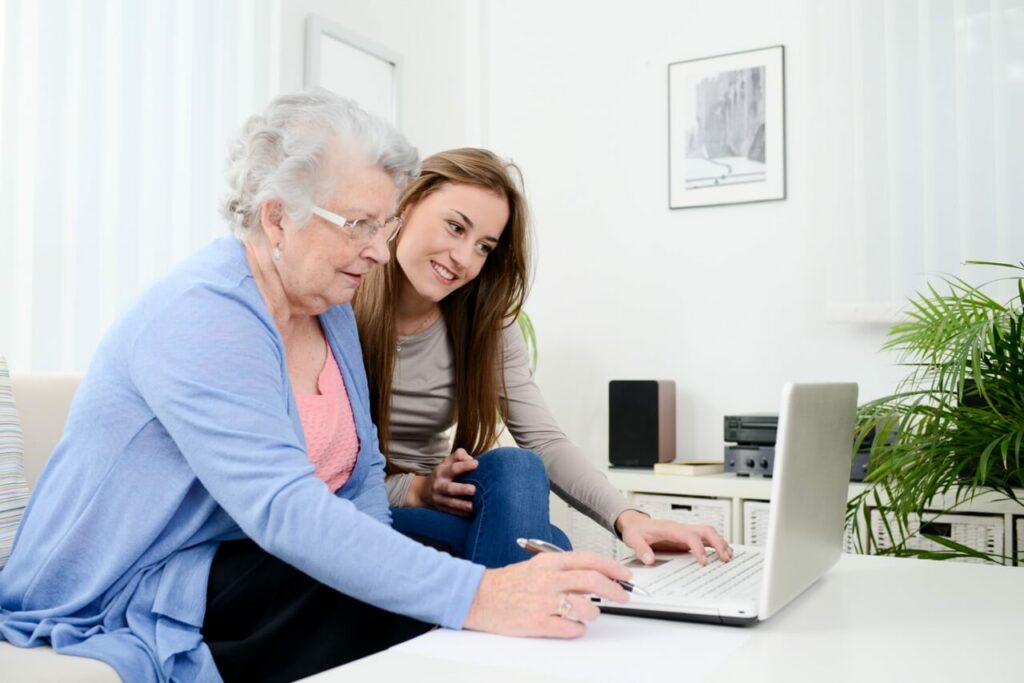 Young Woman helping Old Woman on laptop