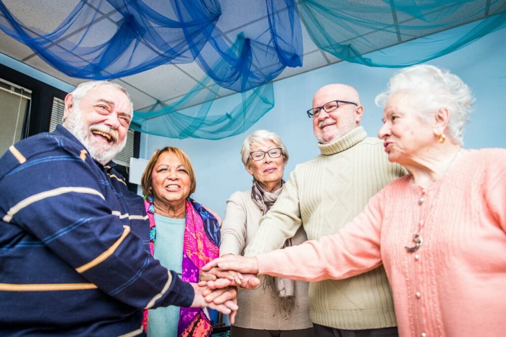 Olderly Elderly people touching hands in a smiling circle